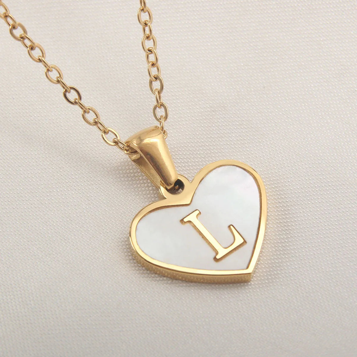Gold-plated heart necklace with white shell pendant showing letter personalisation option