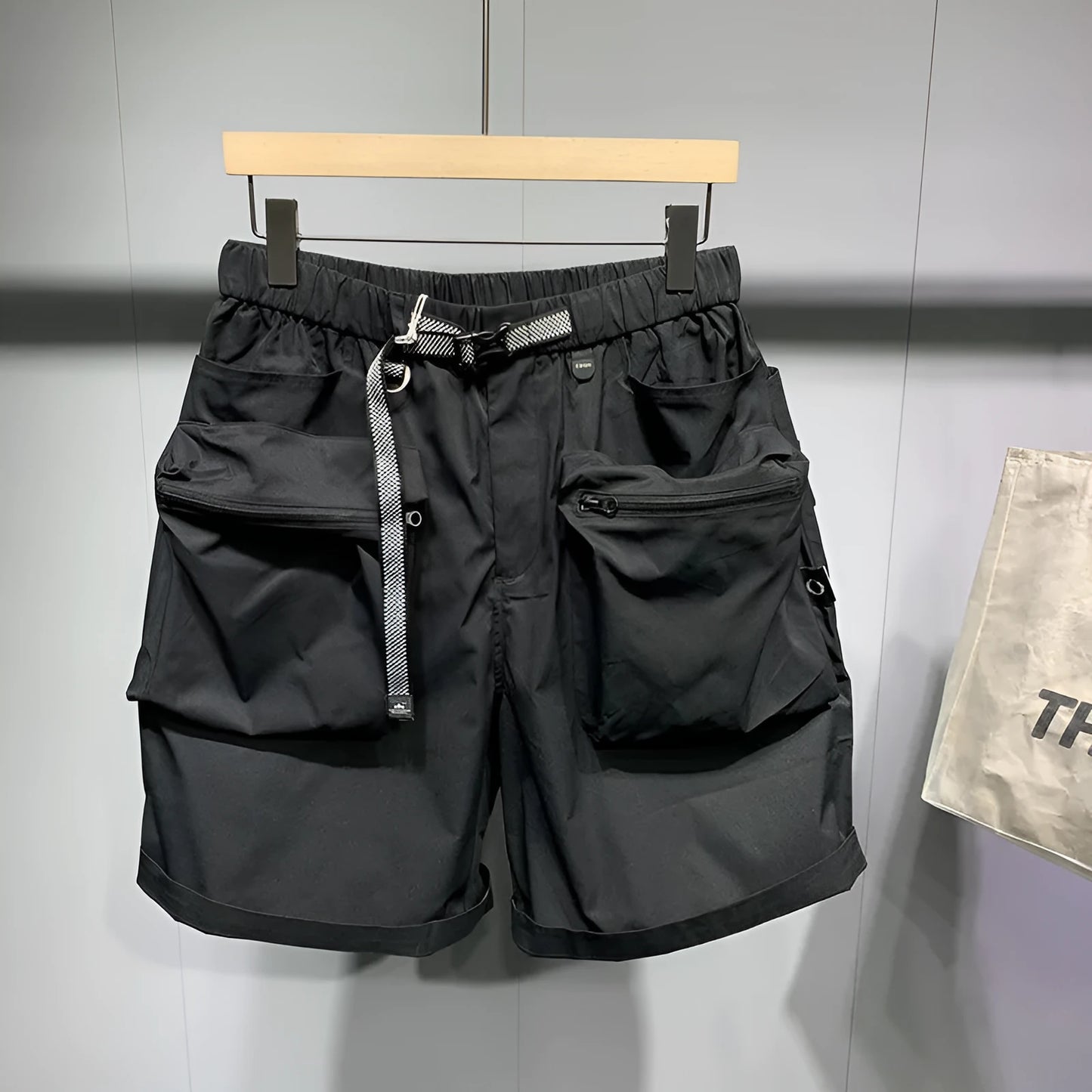 Men's black loose-fit work shorts with multiple pockets showing mid-waist design