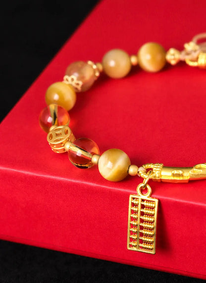Women's handmade beaded bracelet with diamond-shaped tigereye and citrine abacus tag, yellow tower crystals, and copper details.