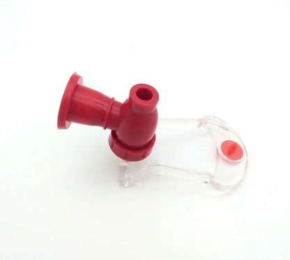 Red plastic Magic Tap soda bottle dispenser attached to an inverted 2-litre bottle on a kitchen table.