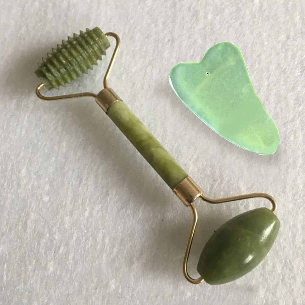 Natural green jade beauty massager with roller and scraper tools on white background