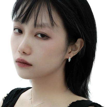 Geometric burnt silver sterling silver ear clip for women on a plain background.