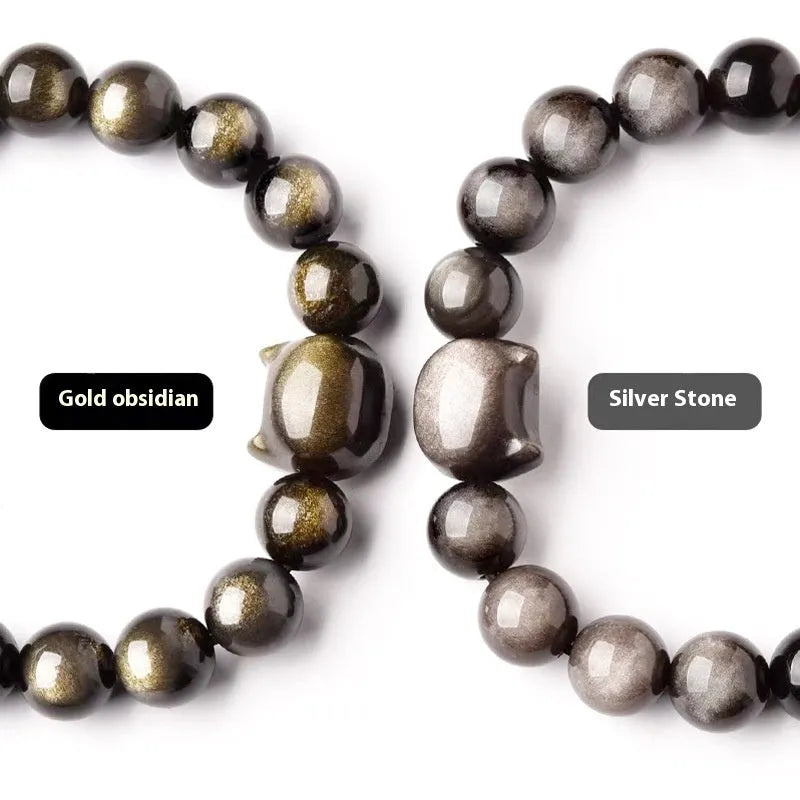 Obsidian cat head bracelet with round stone beads and a gold-toned cat charm on a wrist.