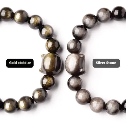 Obsidian cat head bracelet with round stone beads and a gold-toned cat charm on a wrist.