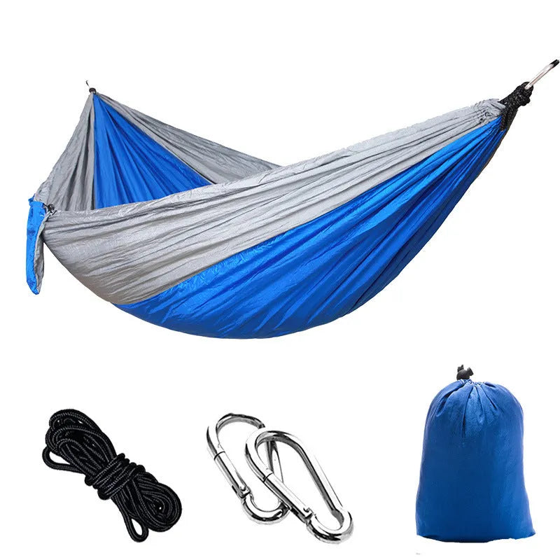 Parachute cloth double camping hammock in chosen colour, with black buckles and round ropes on a tree.