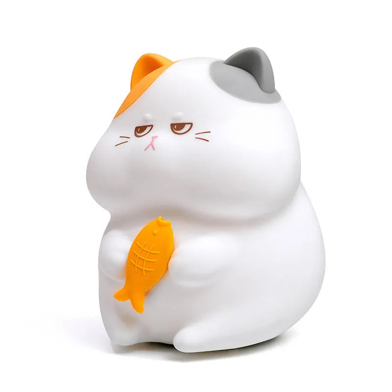 Yellow cartoon Greedy Cat desktop night light with plug, shown on a wooden desk.