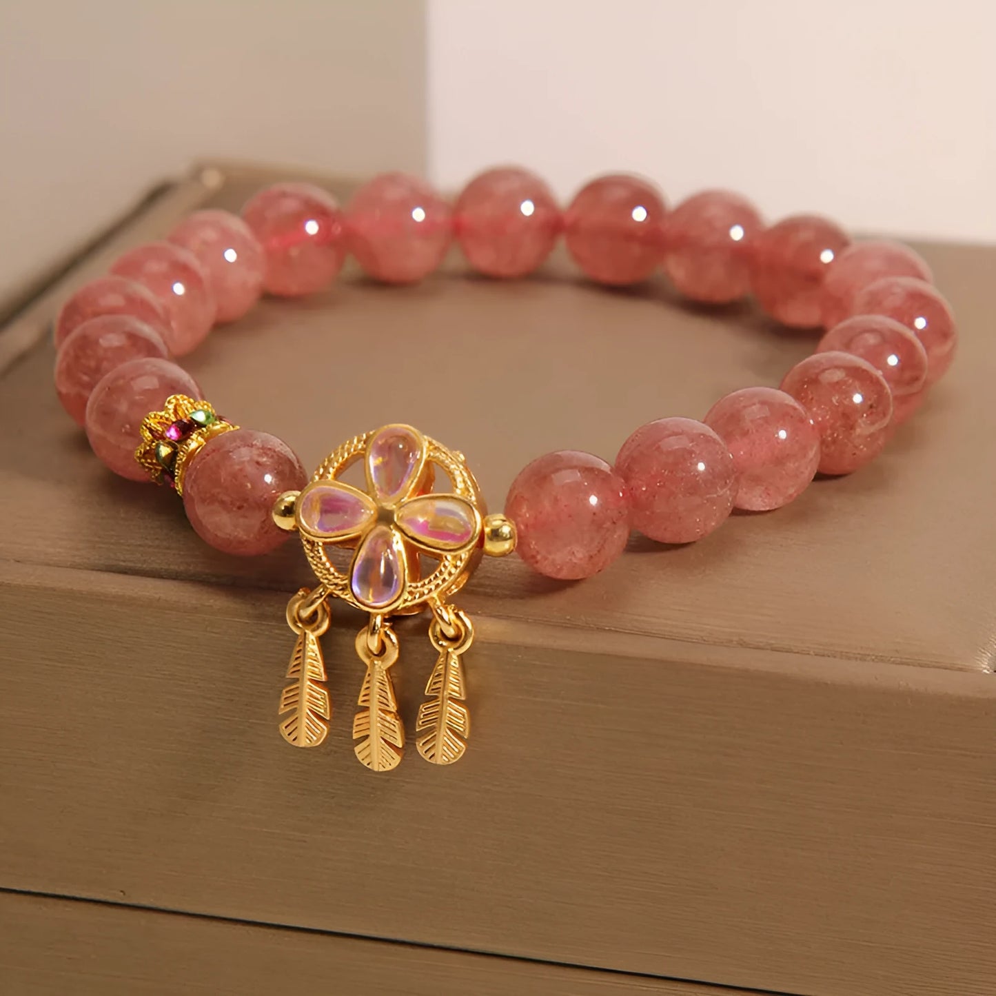 Women's strawberry quartz crystal bracelet with a four-leaf clover dream catcher pendant.