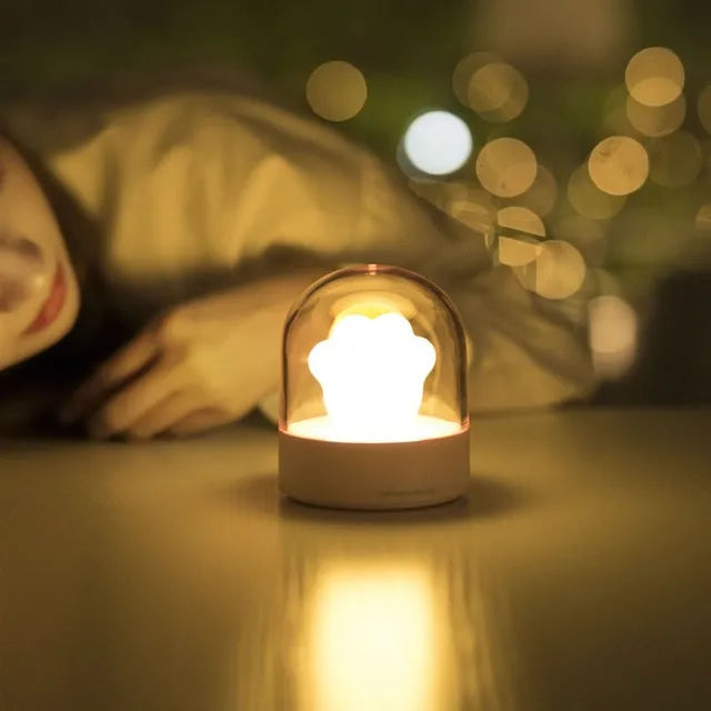 Grey cat paw night light with USB cable on a wooden desk, showing soft glow and detailed paw sculpt.