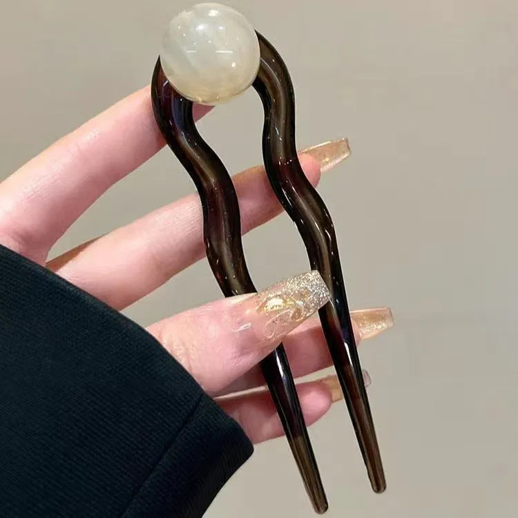 A set of U-shaped acrylic hair barrettes with a simple ball decoration in beige, caramel, and dark grey colours.