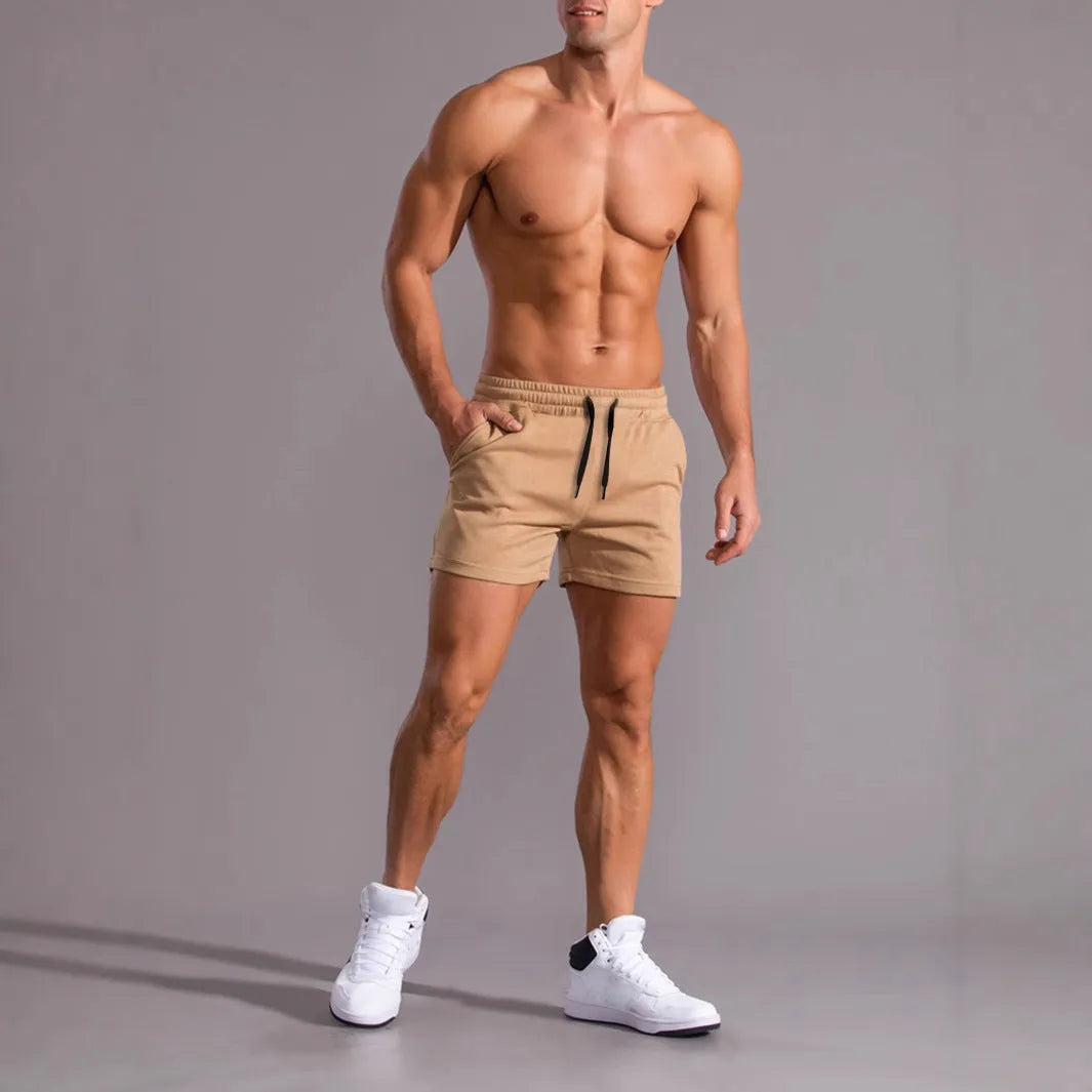 Three pairs of men's solid colour loose-fit drawstring shorts in black, khaki, and light brown laid flat.