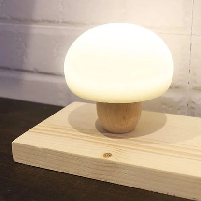 White silicone mushroom-shaped LED night light with a wooden base and touch control.