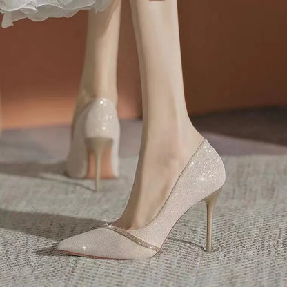 Gold women's stiletto high heels with pointed toe on a plain background.