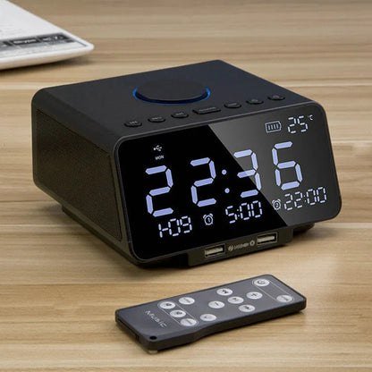 Black and white wireless alarm clock Bluetooth speaker with remote control on a table.