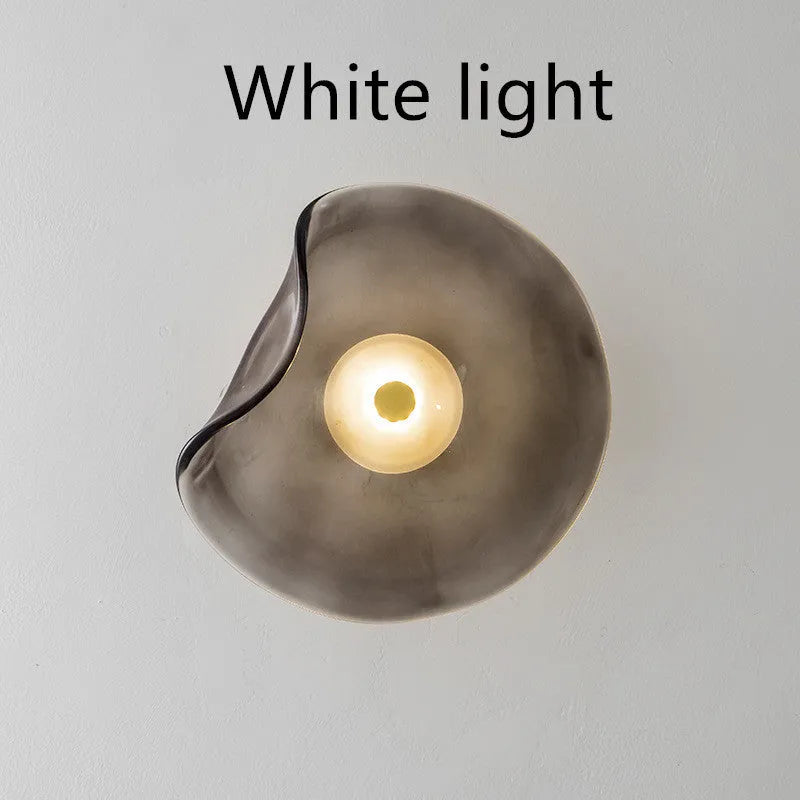 Round glass wall lamp mounted beside bed in cognac colour with 220V operation for bedside lighting
