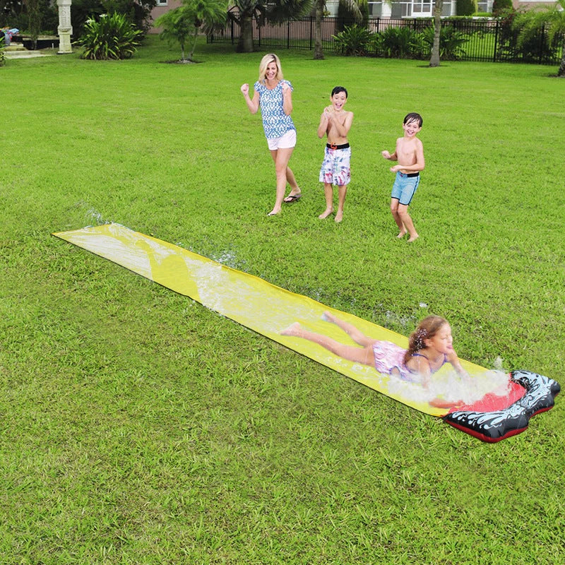 Children playing on a yellow inflatable water slide in a backyard garden