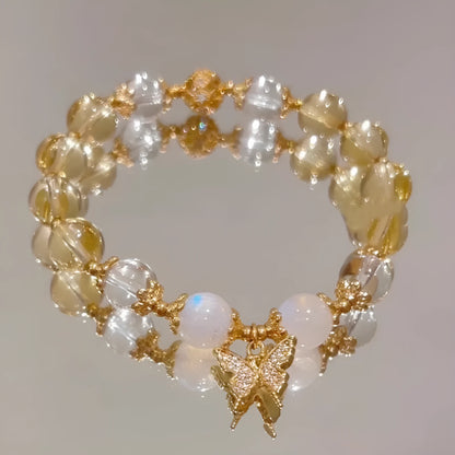 Close-up of a citrine-coloured crystal bracelet with diamond-shaped beads and a butterfly charm.