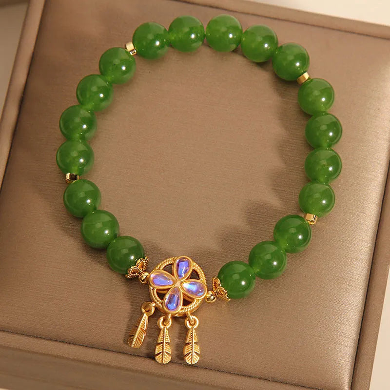 Green jasper crystal four-leaf clover dream catcher pendant on a women's bracelet.