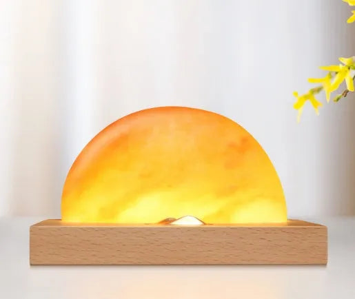 Natural crystal salt lamp with wooden base on a table, wirelessly charging a smartphone.