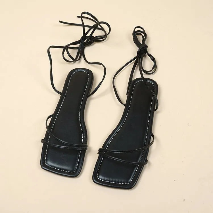 Women's white ankle-ring flat sandals with bandage cloth strap and front lace-up on a rubber sole.