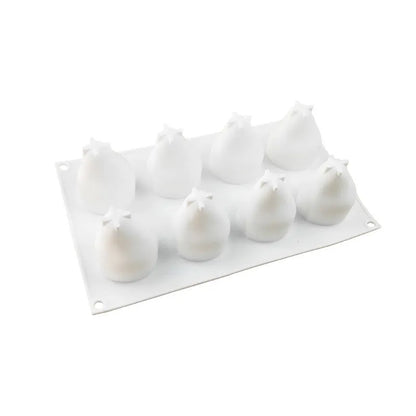 Flexible blue silicone baking mould with six cavities shaped like pineapples and pine cones on a kitchen counter.