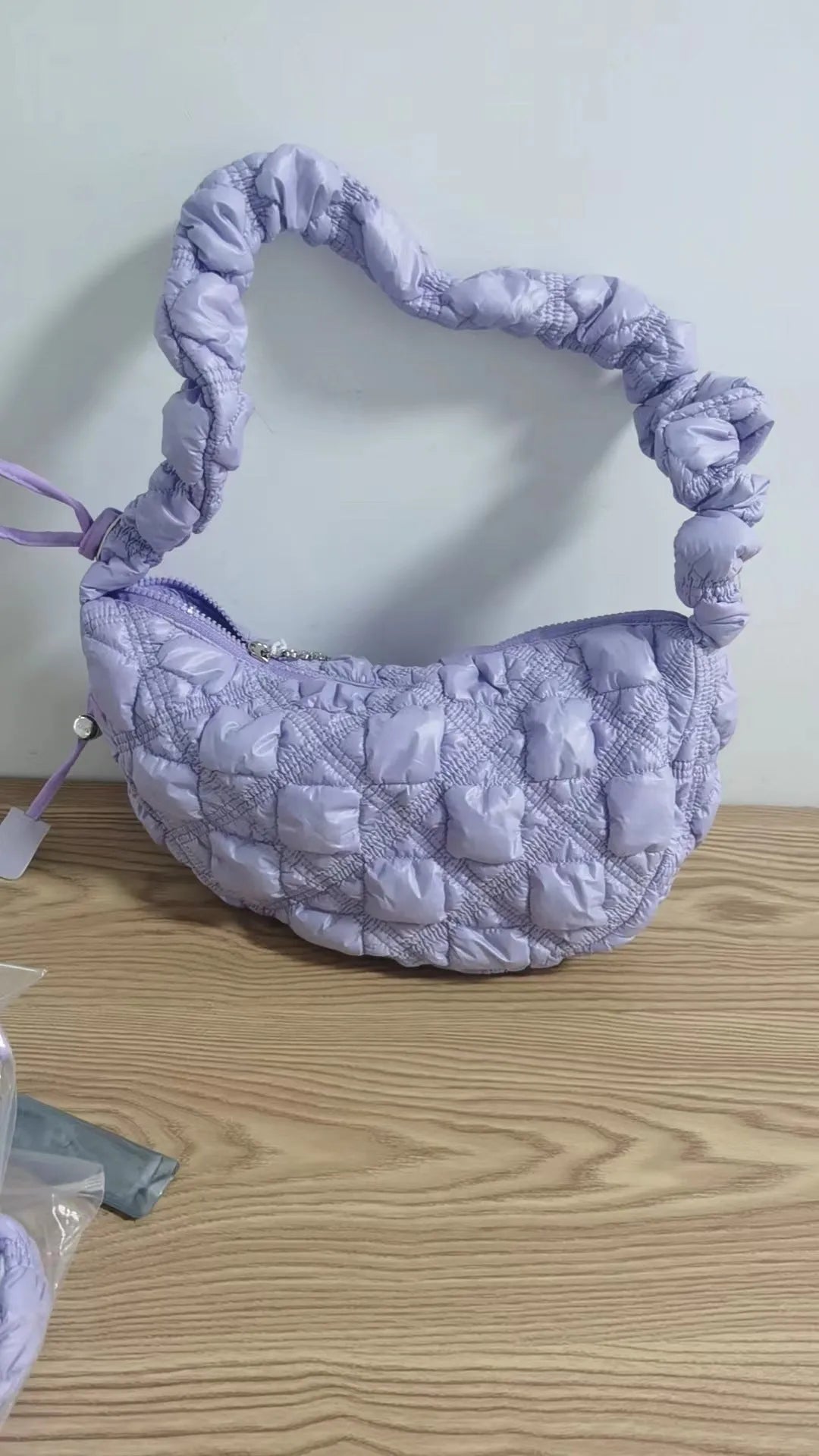 Women's light grey nylon underarm messenger bag with adjustable long strap, shown worn crossbody.