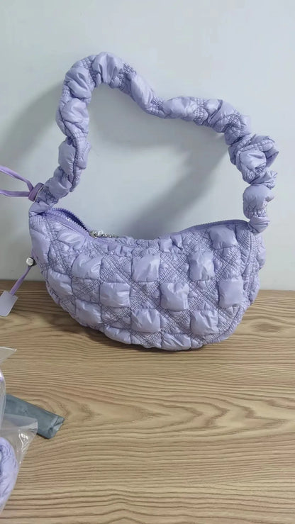Women's light grey nylon underarm messenger bag with adjustable long strap, shown worn crossbody.