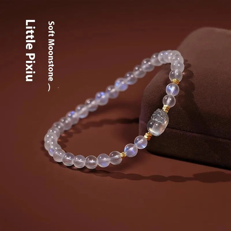 Close-up of a women's moonstone bracelet with an animal or Zodiac motif on a blue background.