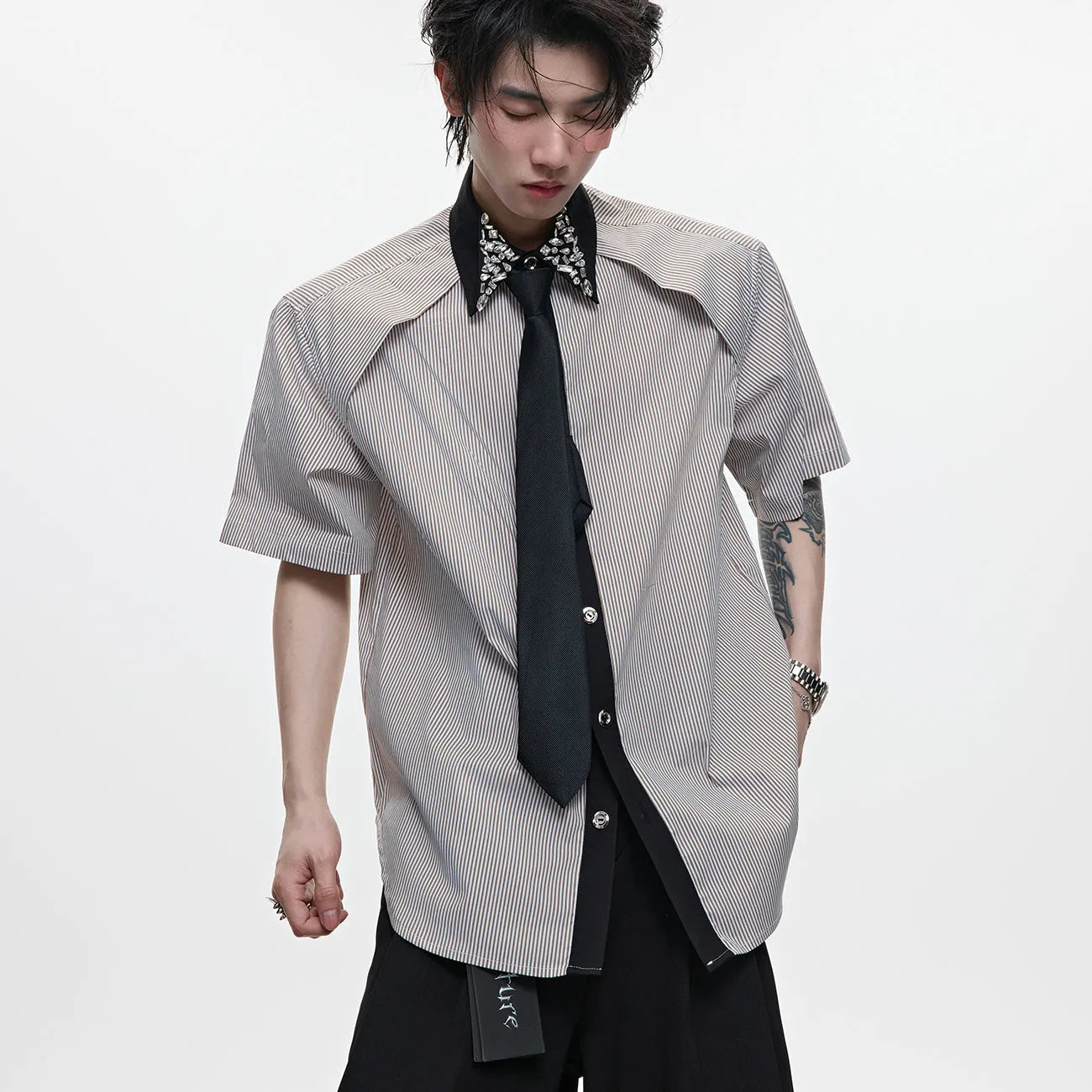Man wearing a blue loose fit men's shirt with a diamond tie collar and patchwork striped design.