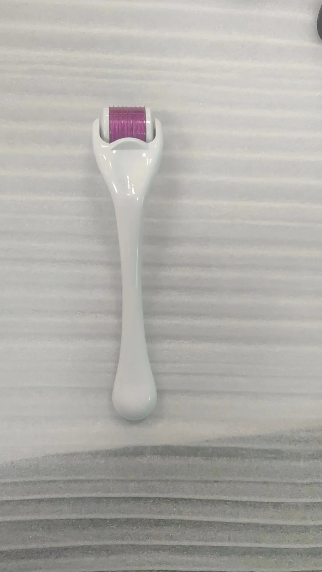 Sterile micro needle derma roller with black handle and coloured wheel on white background