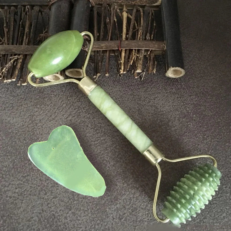 Natural green jade beauty massager with roller and scraper tools on white background