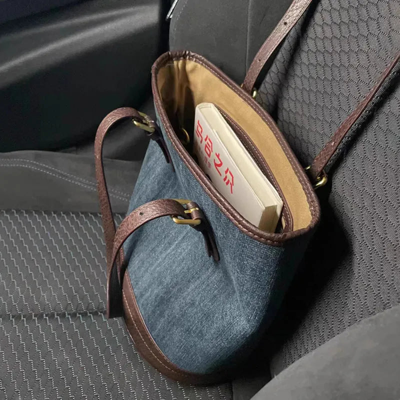 Large blue denim patchwork bucket handbag with one shoulder strap.