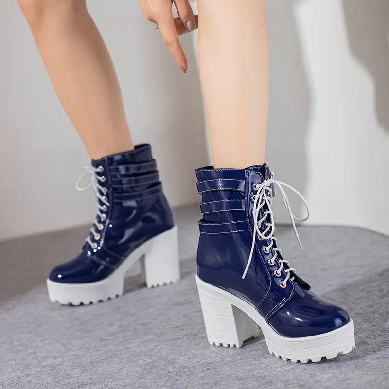 Women's black chunky heel ankle boots with round toe and front lace-up on a wooden floor.