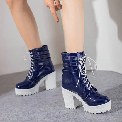 Women's black chunky heel ankle boots with round toe and front lace-up on a wooden floor.