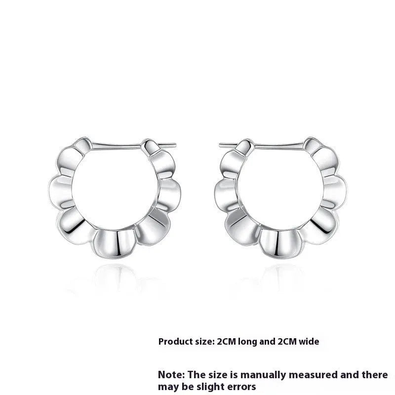 A pair of shiny silver geometric stud earrings with a round design on a plain background.