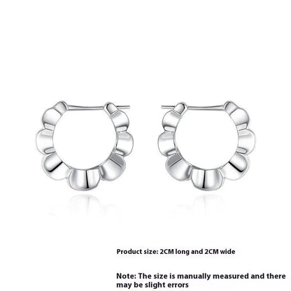 A pair of shiny silver geometric stud earrings with a round design on a plain background.