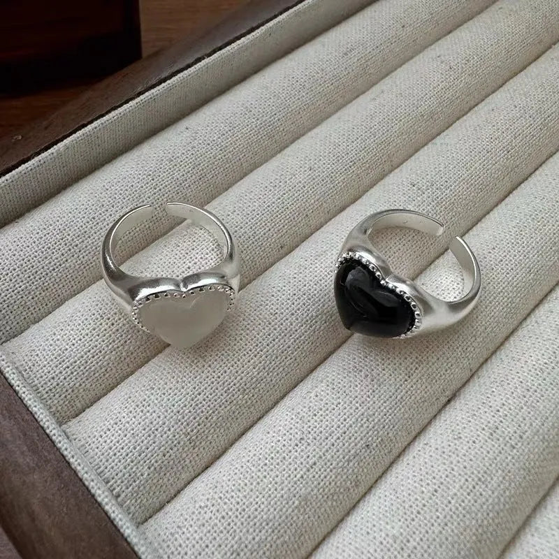 Adjustable sterling silver ring with a heart-shaped black agate stone in a niche setting on a woman's finger.