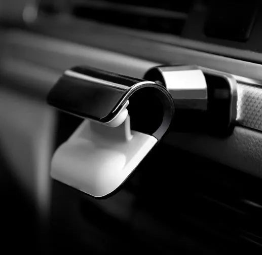 Black universal car phone holder with 360-degree rotation mounted on a car air vent, holding a mobile phone.