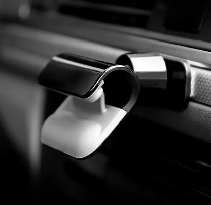 Black universal car phone holder with 360-degree rotation mounted on a car air vent, holding a mobile phone.