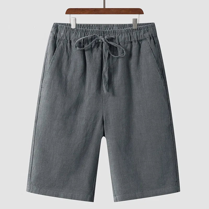 Men's beige linen casual shorts with a loose fit and elastic waistband on a neutral background.