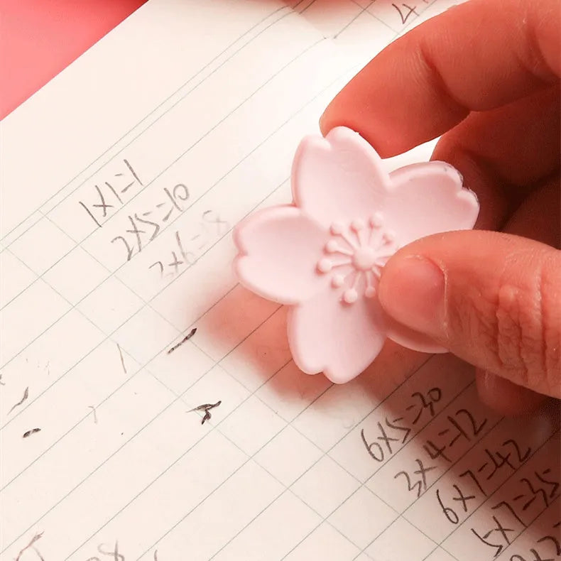 Assorted colourful cherry blossom shaped student erasers on a white background.