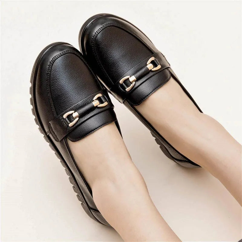 Black casual pumps with round toe, low flat heel, soft bottom, and a subtle metal detail on the upper.