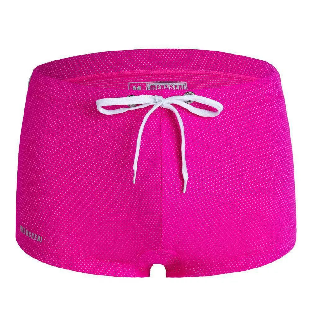 Men's low waist swim trunks in stretch nylon on a man, showing elastic waistband and boxer-style cut.
