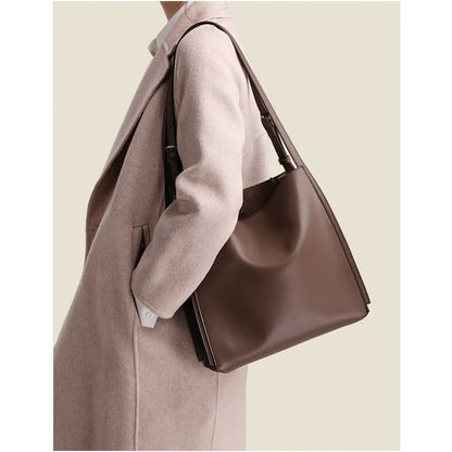 Brown genuine leather women's bucket-style commuter bag with double shoulder straps showing internal compartments