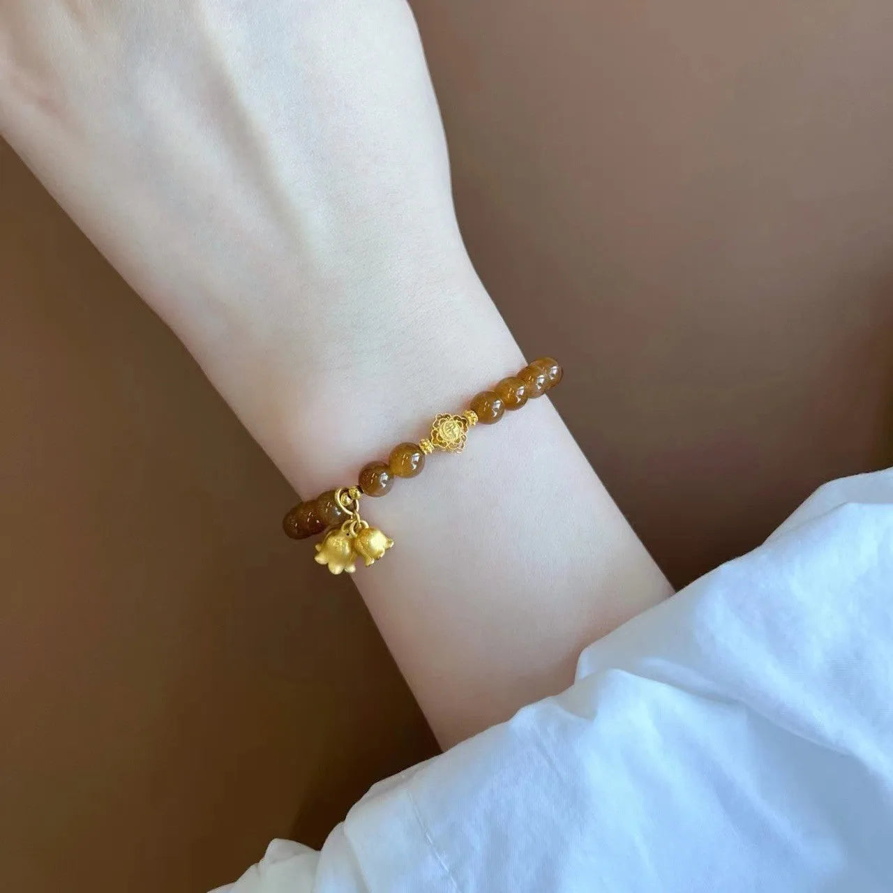 Caramel-coloured women's bracelet with beeswax Lily, music note, and blessing charms in New Chinese style.