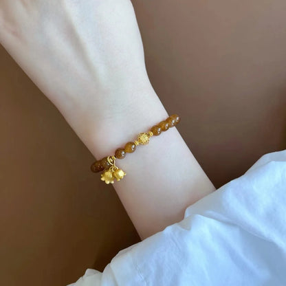 Caramel-coloured women's bracelet with beeswax Lily, music note, and blessing charms in New Chinese style.