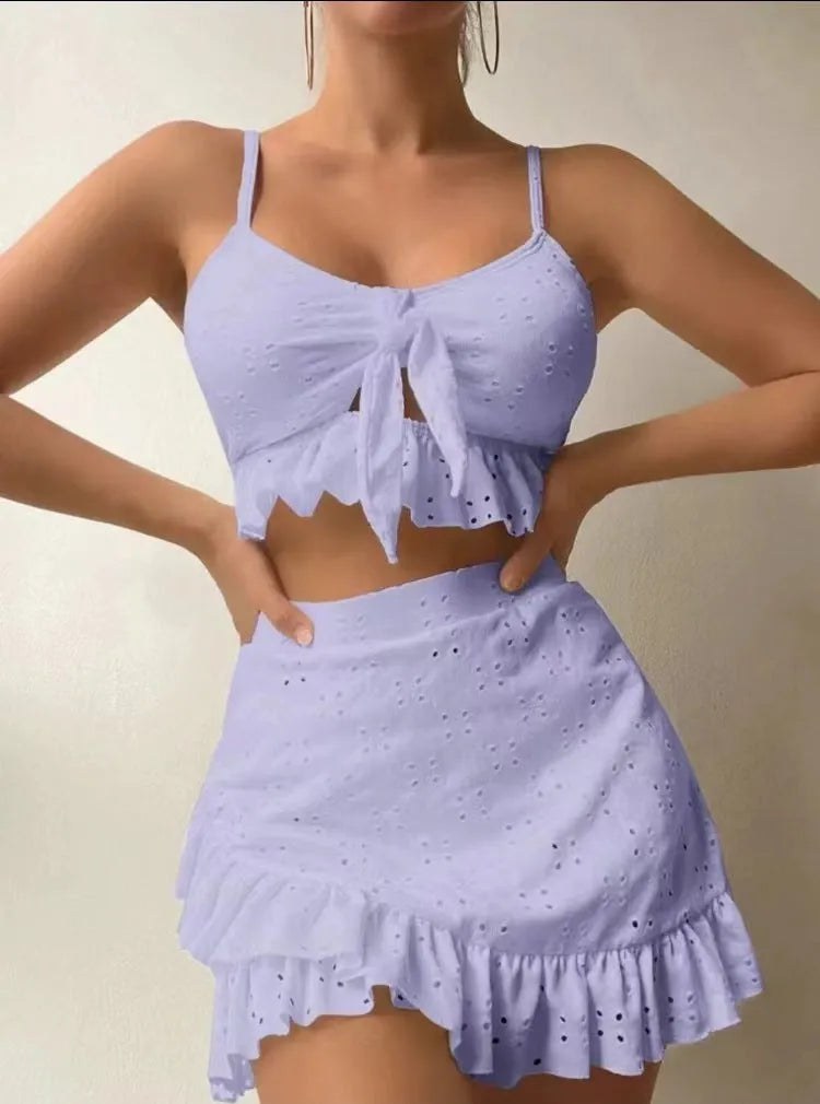 Women's solid colour three-piece bikini swimsuit with a split hip skirt.