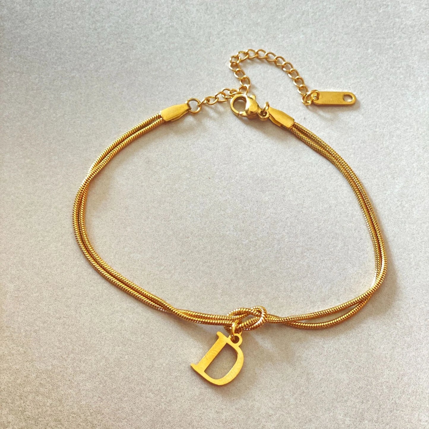 Elegant letter charm bracelets for women in gold and silver tones, featuring a delicate snake chain design and personalised letter charms.