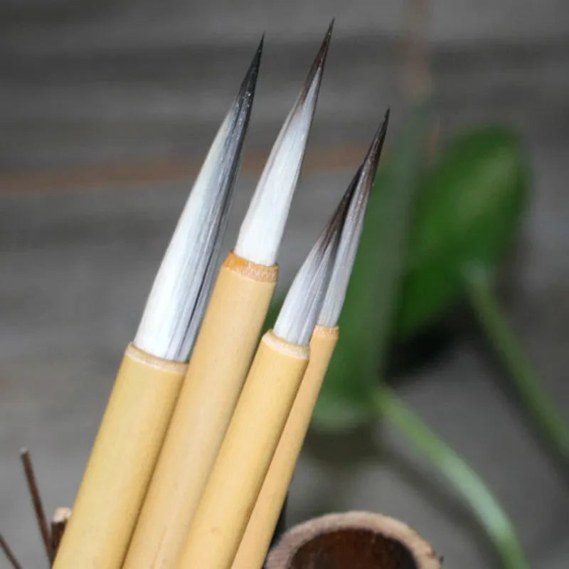 Four traditional writing brushes with gold bodies, wolf wool hair, and pine branch colour