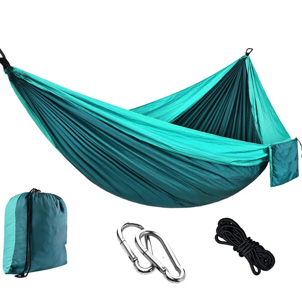 Parachute cloth double camping hammock in chosen colour, with black buckles and round ropes on a tree.