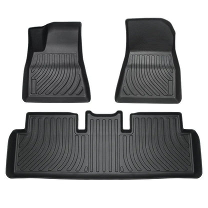 Custom black rubber floor mats fitted in a Tesla Model 3, showing textured surface and TPE driver footrest.